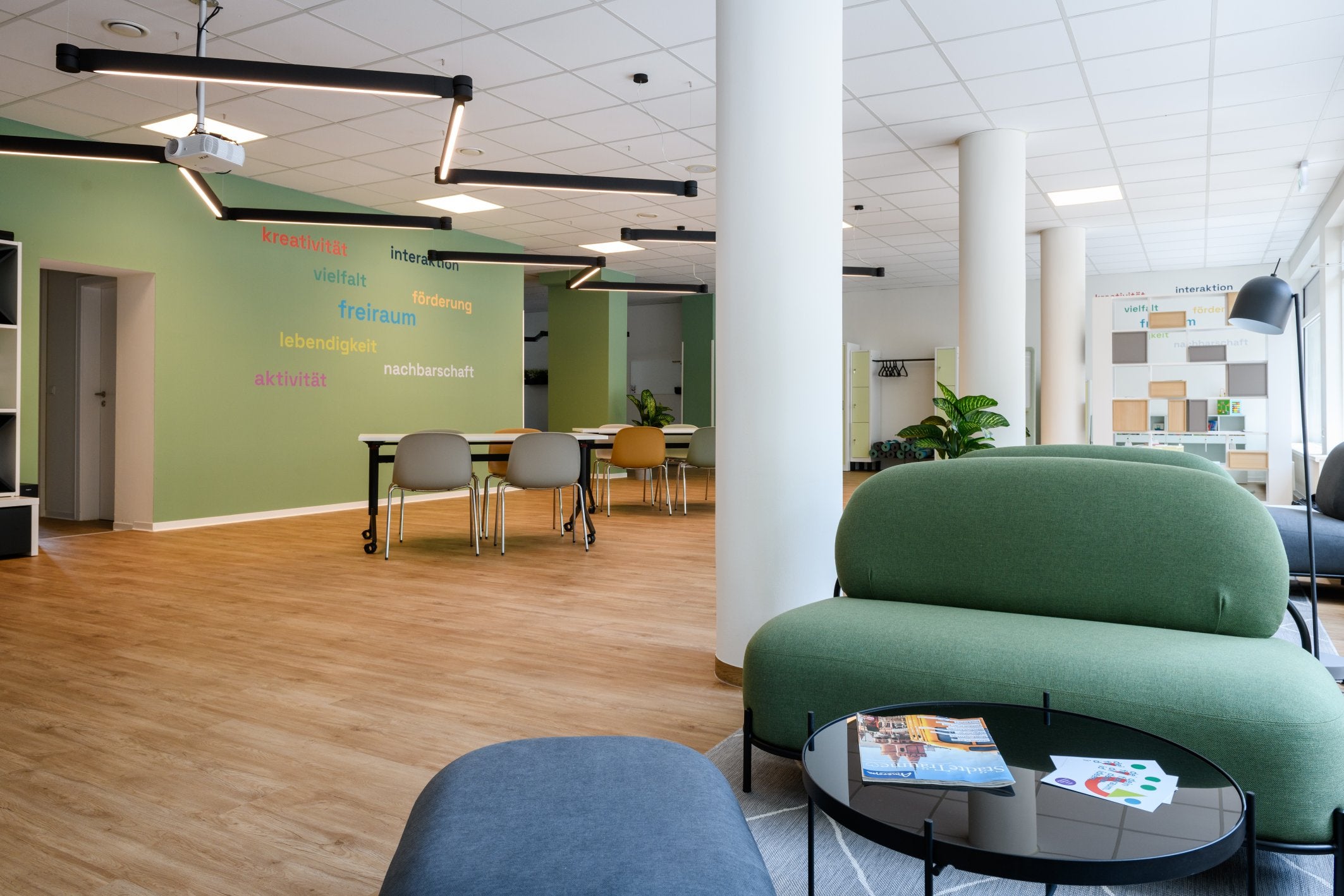 Großer, heller Raum mit mehreren bequemen Sitzmöglichkeiten und einer grünen Wand.