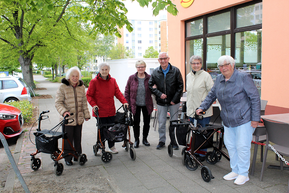 Eine Gruppe von Senioren stehen zusammen vor einem Restaurant. Eine Gruppe von Senioren stehen zusammen vor einem Restaurant.