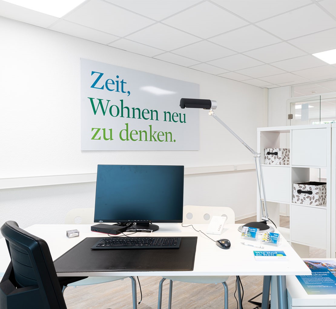 Schreibtisch mit Computer und Lampe in einem modernen Büro.