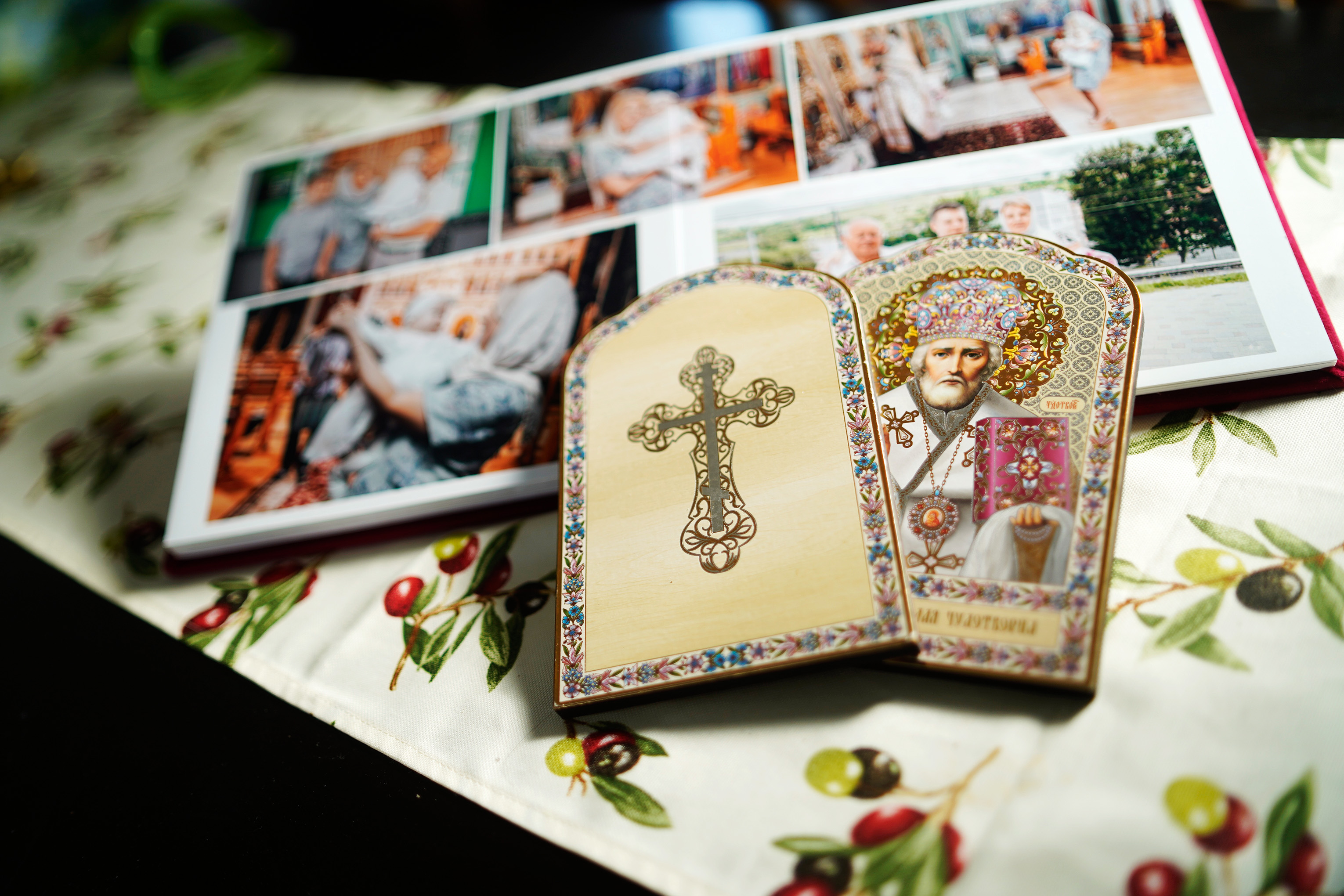 Fotoalbum und Ikone liegen auf einem Tisch mit Tischdecke.