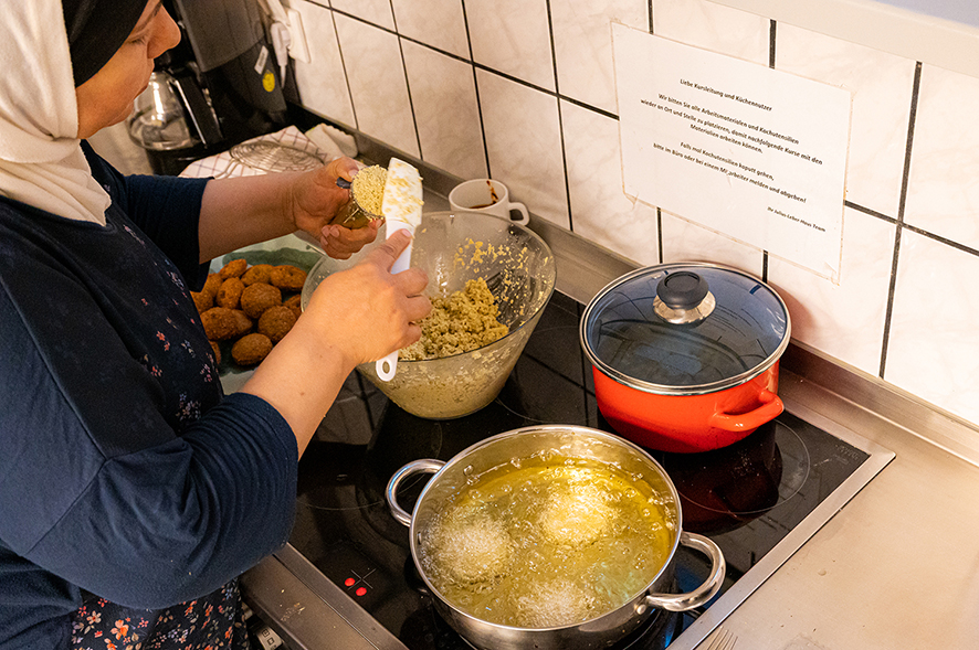 Person formt Falafel in einer Küche, neben einem Topf Öl.