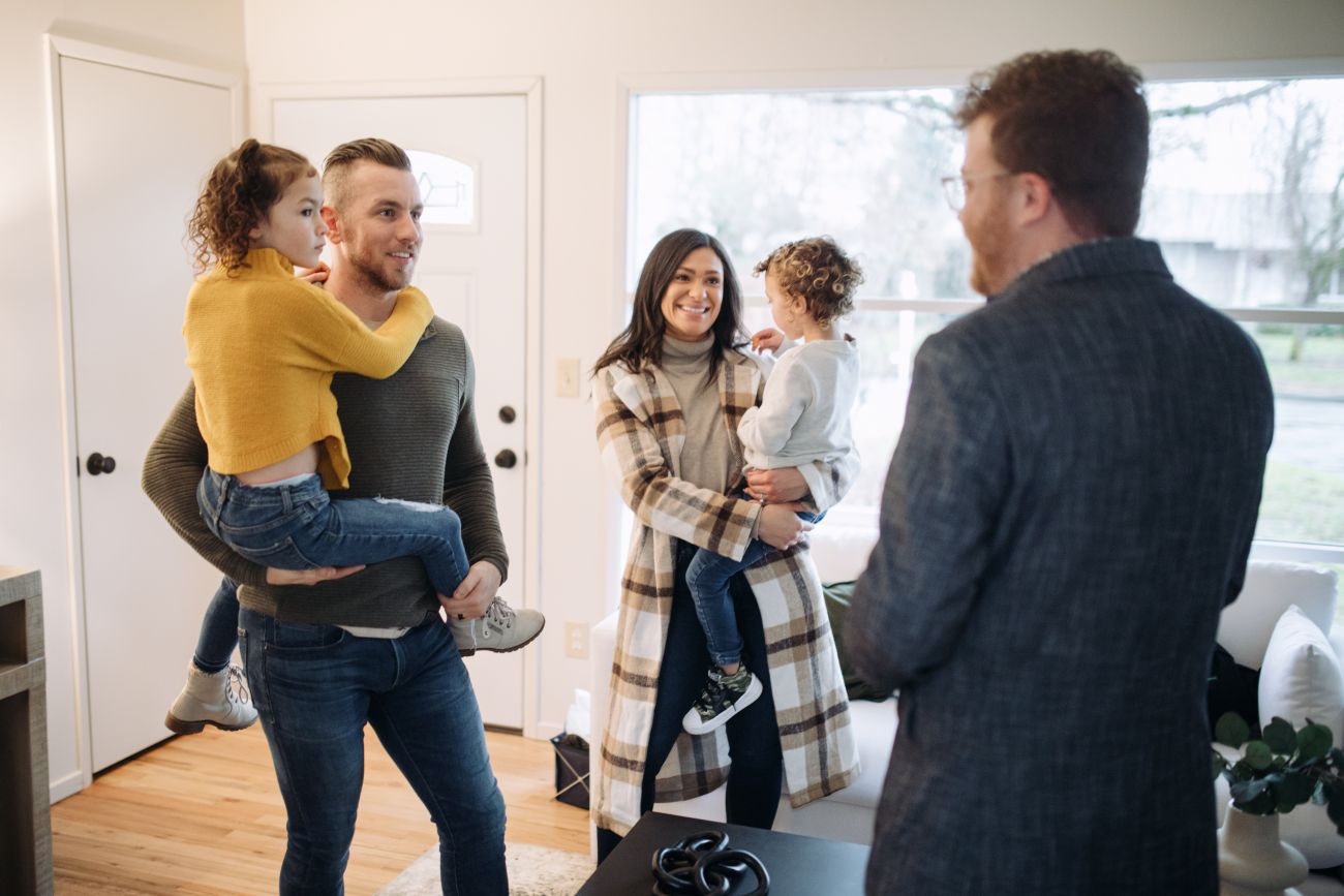 Familie mit zwei Kindern bei der Wohnungsbesichtigung im Gespräch mit dem Vermieter.