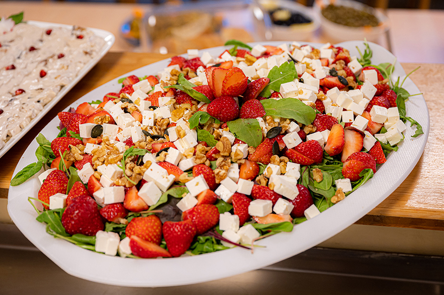 Erdbeer-Feta-Salat auf einem weißen Teller, auf Holztresen.