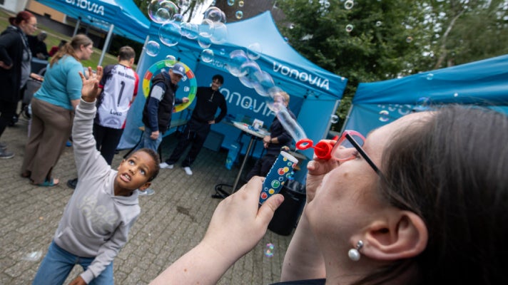 Eine Frau macht für ein Kind Luftblasen vor Vonovia Ständen auf dem Mieterfest im Dortmund.