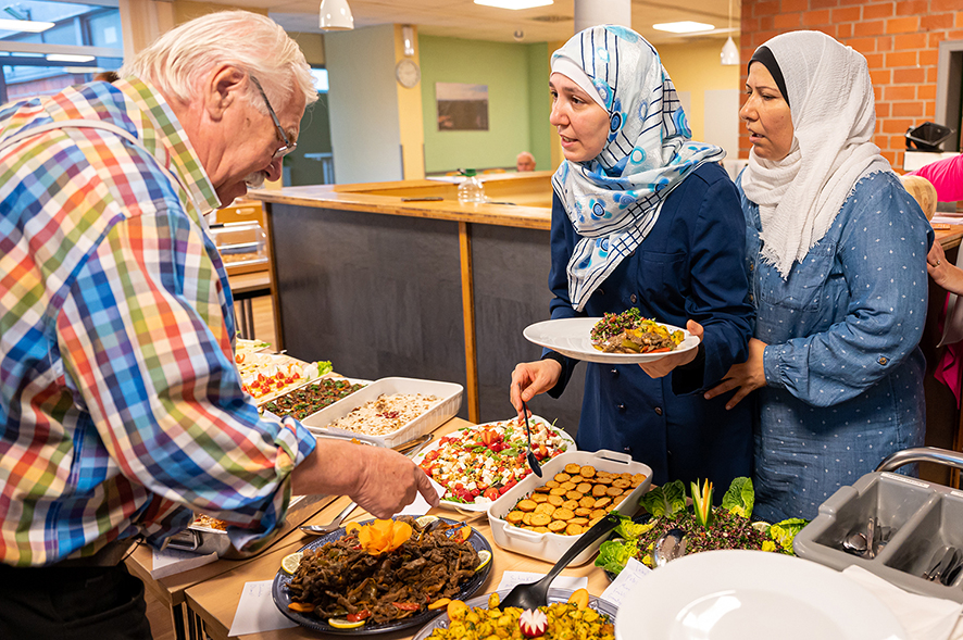 Älterer Mann und zwei Frauen wählen Essen in einer Kantine.