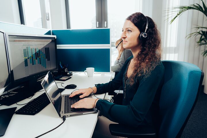 Frau arbeitet am Laptop im modernen Büro mit Headset. Frau arbeitet am Laptop im modernen Büro mit Headset.